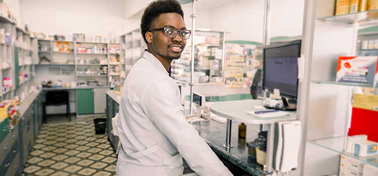 pharmacy technician logs orders into the computer at pharmacy counter